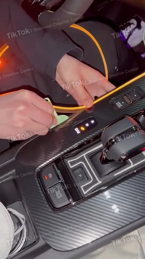Hands tucking the LED wire into car console trim